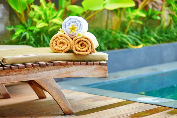 Toallas con flores de frangipani blancas cerca de la piscina —  Fotos de Stock