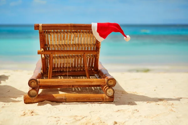 Chapéu de Papai Noel em chaise longue na praia de areia branca — Fotografia de Stock