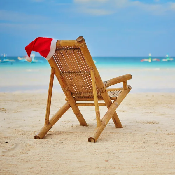 Chapéu de Papai Noel em chaise longue na praia de areia branca — Fotografia de Stock