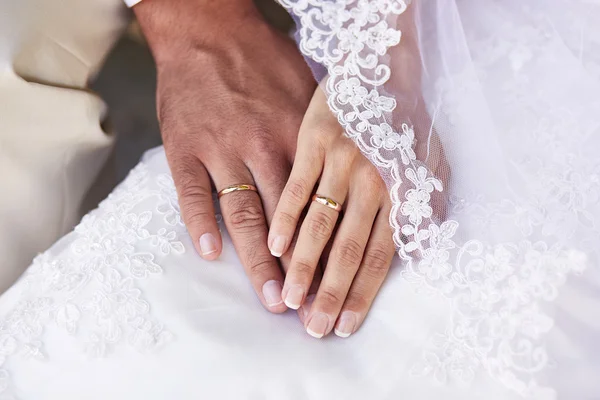 Couple holding hands against wedding dress — Stock Photo, Image