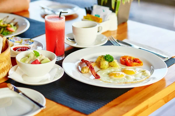 Fried eggs, fruit salad and juice for breakfast — Stock Photo, Image