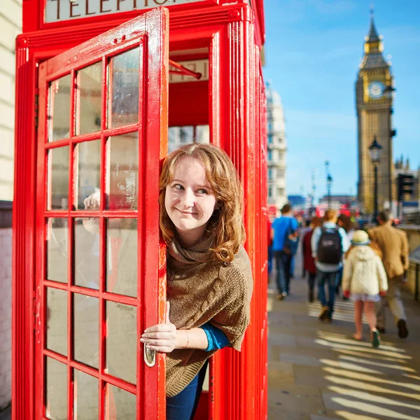 Turista feliz olhando para fora da caixa de telefone vermelho — Fotografia de Stock