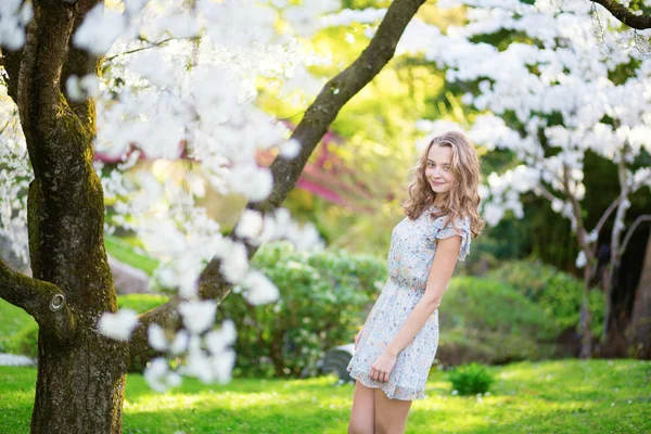 Beautiful young girl in cherry blossom garden — Stock Photo, Image