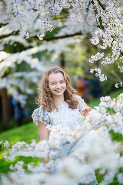 Beautiful young girl in cherry blossom garden — Stock Photo, Image