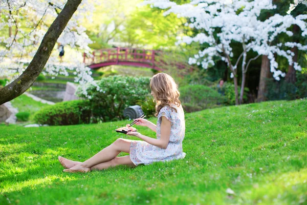 Meisje sushi eten in kersenbloesem tuin — Stockfoto