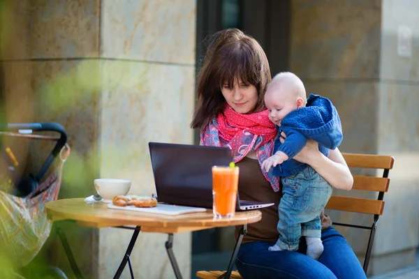 Young mother with her baby boy working in cafe — Stock Photo, Image