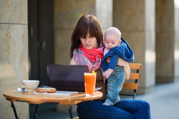 Jeune mère avec son bébé garçon travaillant dans un café — Photo