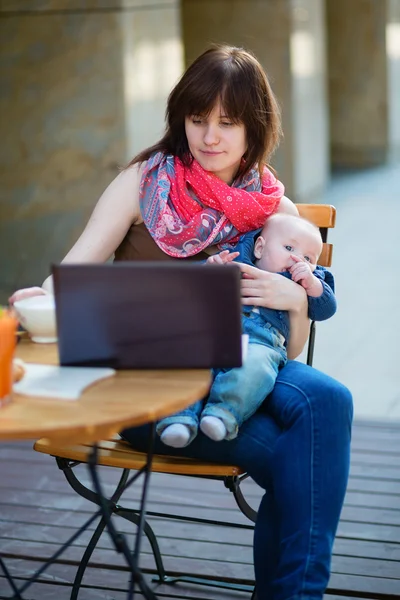 Young mother with her baby boy working in cafe — Stock Photo, Image