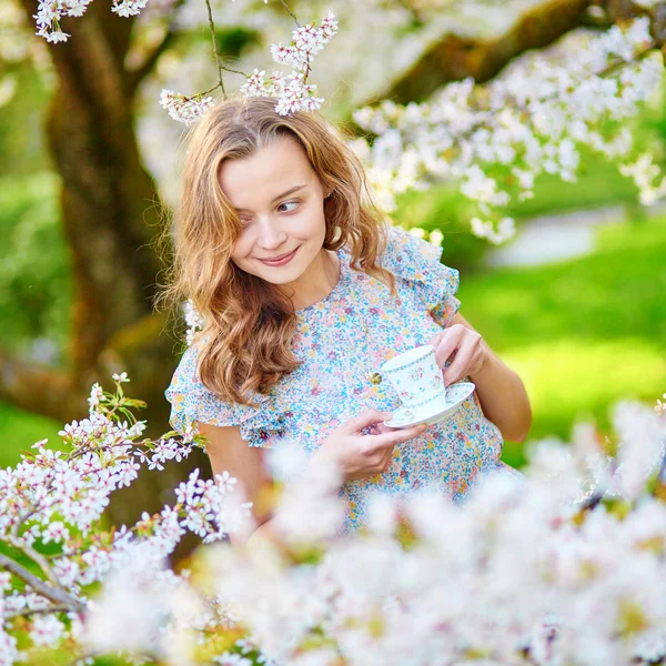 Žena v zahradě třešňový květ s šálkem čaje — Stock fotografie