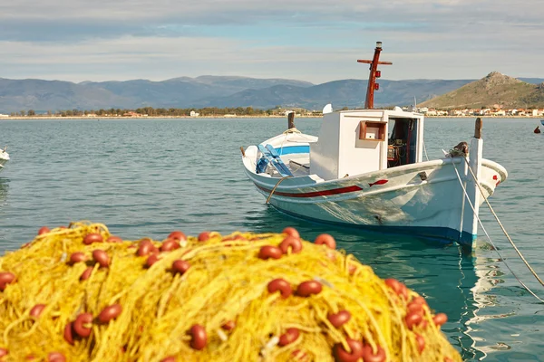 Barco branco e pilha de redes de pesca amarelas no porto — Fotografia de Stock