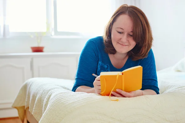 Girl writing into diary or planning her day — Stock Photo, Image