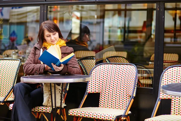 Mujer joven con un libro en la cafetería — Foto de Stock