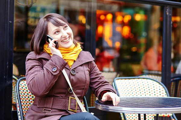 Ung flicka talar på thephone i parisisk café — Stockfoto