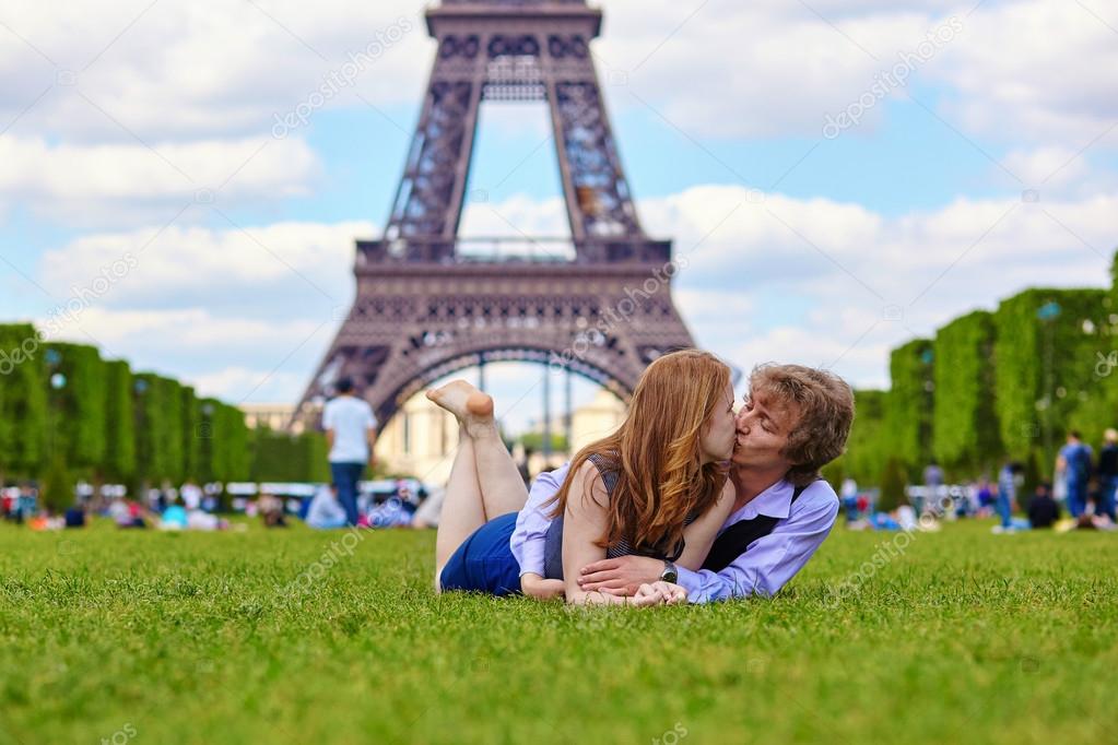 Laughing couple lying on the grass in Paris