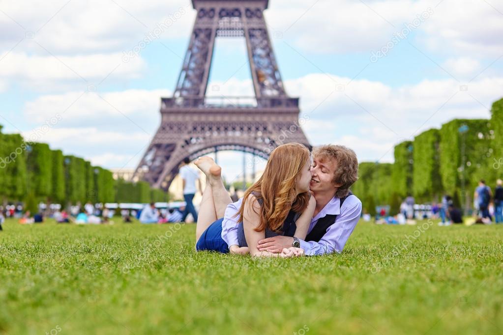 Laughing couple lying on the grass in Paris