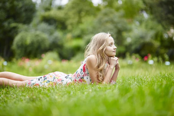 Jong meisje liggen op het gras op een zomerdag — Stockfoto