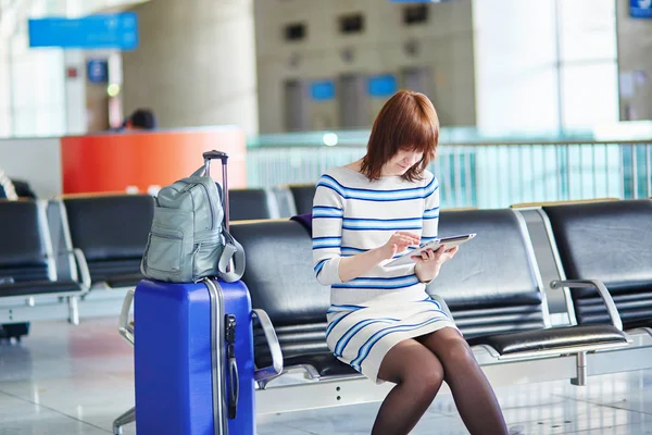 Young passenger at the airport, using her tablet — Stock Photo, Image