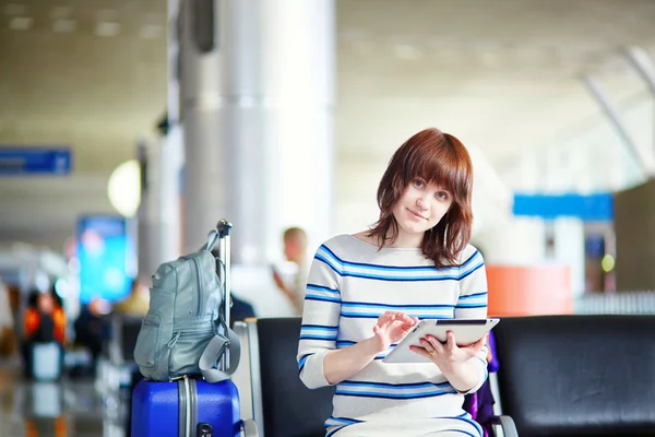 Молодая пассажирка в аэропорту, пользуется планшетом — стоковое фото