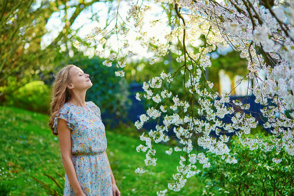 Beautiful young girl in cherry blossom garden on a spring day