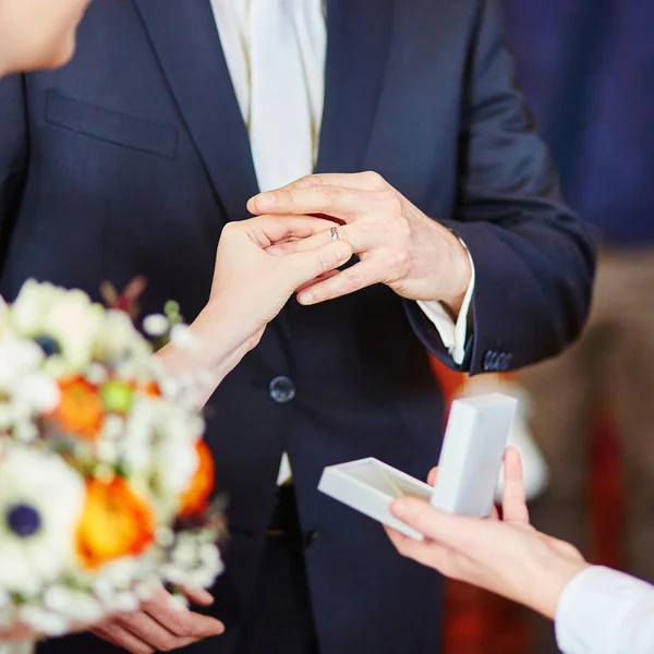 Novia poniendo el anillo en el dedo del novio — Foto de Stock