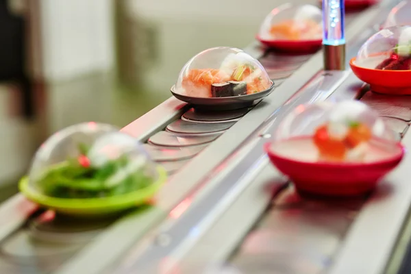 Sushi plates on rails in restaurant — Stock Photo, Image