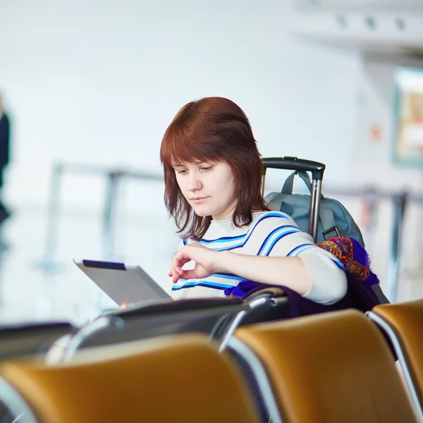 Молодая пассажирка в аэропорту, пользуется планшетом — стоковое фото