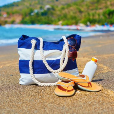 Plaj çantası, flip flop ve güneş koruyucu şişe