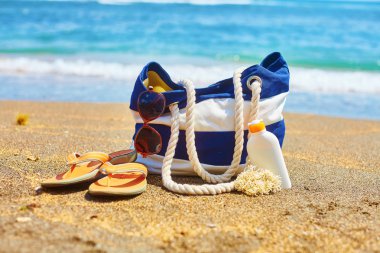 Plaj çantası, flip flop ve güneş koruyucu şişe