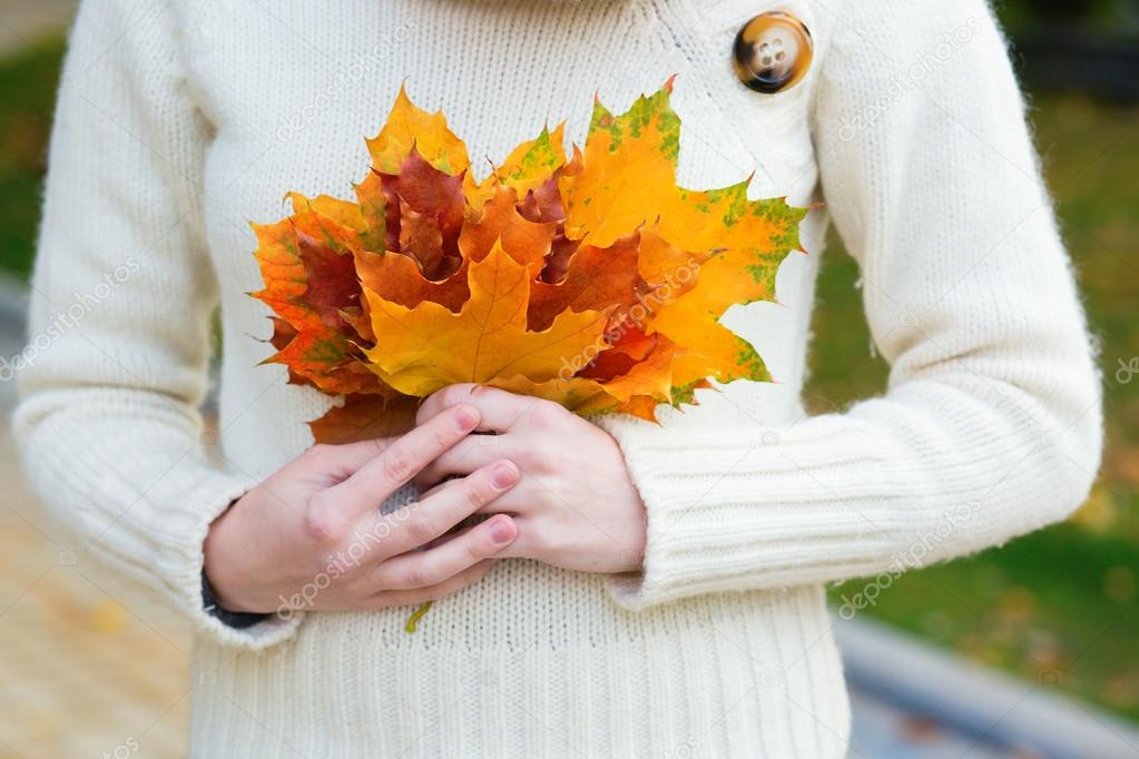 girl holding a bunch of autumn leaves in her hands