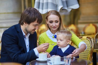 Happy family of three in Parisian cafe
