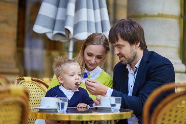 Happy family of three in Parisian cafe