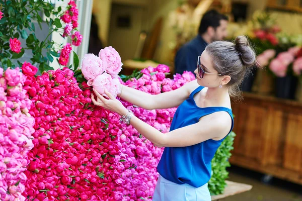 Parisian woman selecting peonies in flower shop — Stock Photo, Image