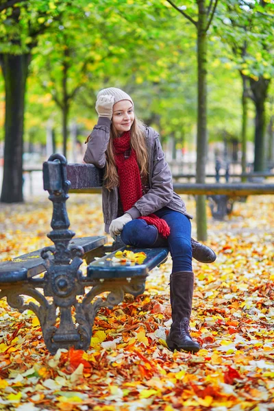 Menina sentada em um banco no parque em um dia de outono — Fotografia de Stock