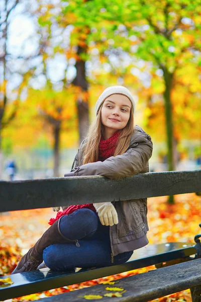 Girl sitting on a bench in park on a fall day — Stock Photo, Image