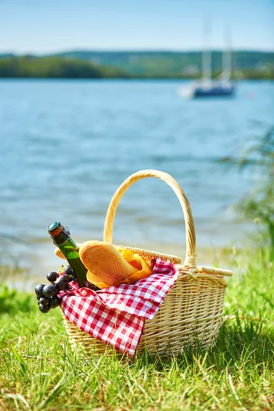 Piknik sepeti suya yakın gıda ile — Stok fotoğraf