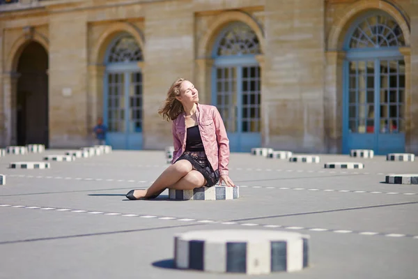 Žena sedí na jednom z Colonnes de Buren v Paříži — Stock fotografie