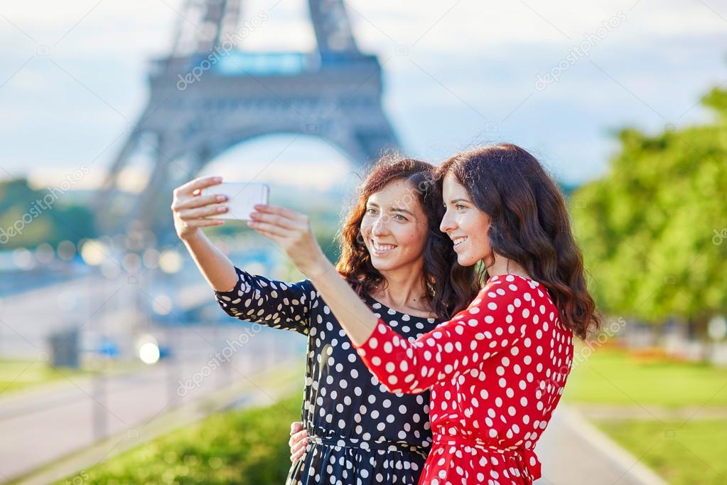 Beautiful twin sisters taking selfie in front of Eiffel Tower