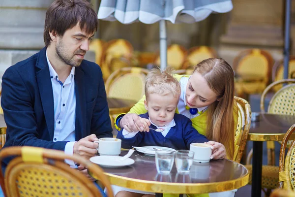 Familia feliz de tres en un café parisino al aire libre —  Fotos de Stock
