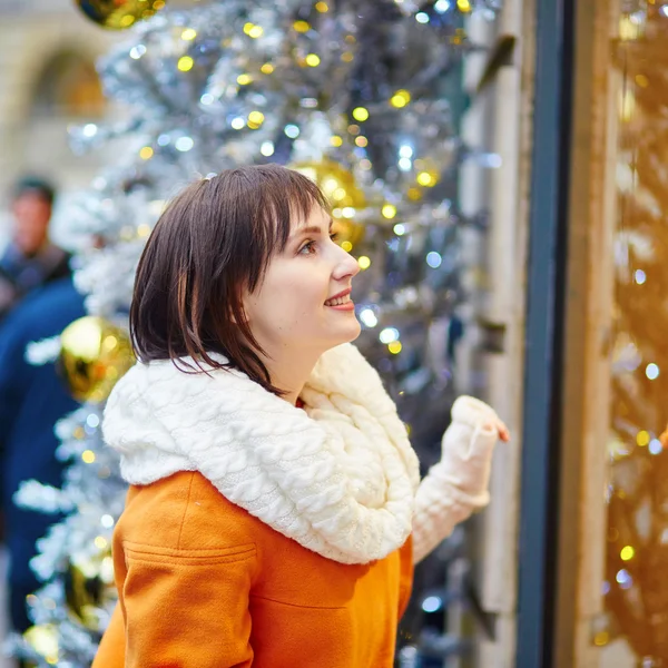 Девушка смотрит на парижские витрины, украшенные на Рождество — стоковое фото
