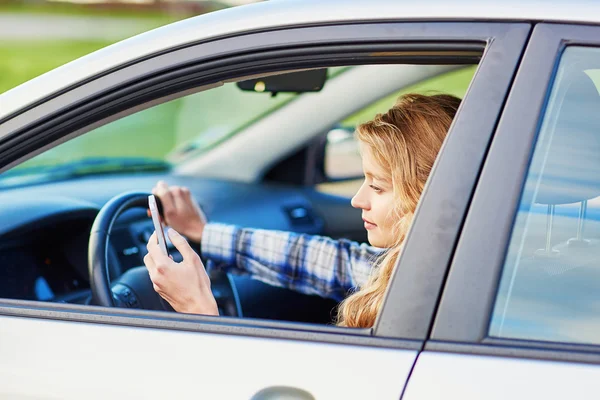 Mulher usando seu smartphone enquanto dirige um carro — Fotografia de Stock