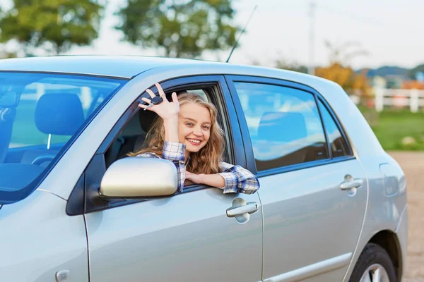 Beautiful young driver looking out of the car holding key — Stock Photo, Image