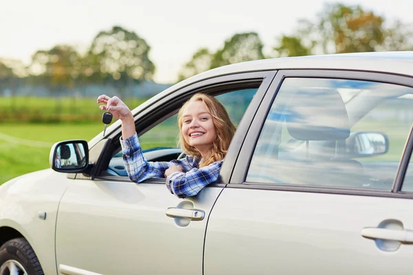 Όμορφη νεαρός οδηγός ψάχνει έξω από το αυτοκίνητο που κρατάτε το πλήκτρο — Φωτογραφία Αρχείου