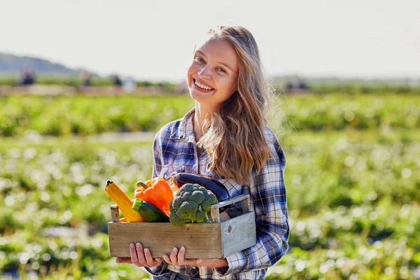 Young woman holding wooden crate with vegetables — Stock Photo, Image