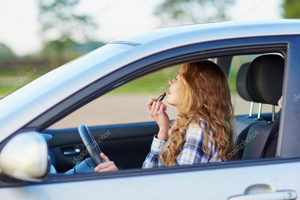 Woman applying lipstick in a car while driving