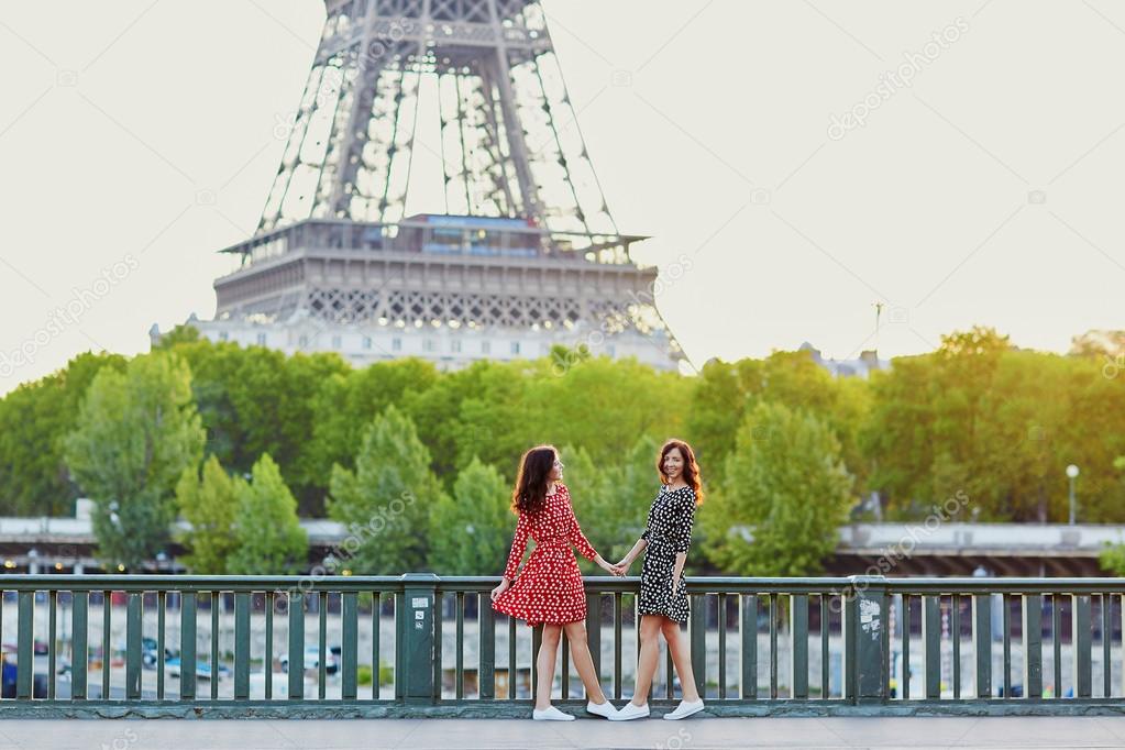 Beautiful twin sisters in front of the Eiffel tower in Paris