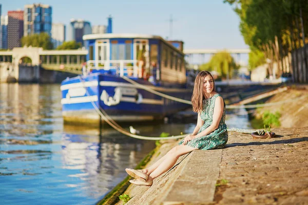 Glad ung tjej sitter på stranden av Seine — Stockfoto