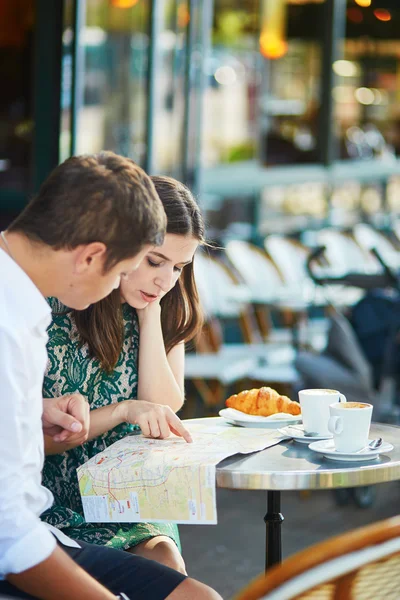 Молодая романтическая пара с картой во французском кафе — стоковое фото