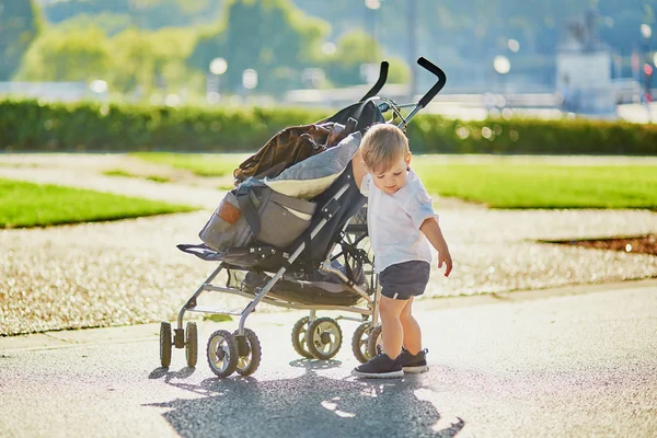 Schattige kleine jongen duwen zijn wandelwagen — Stockfoto