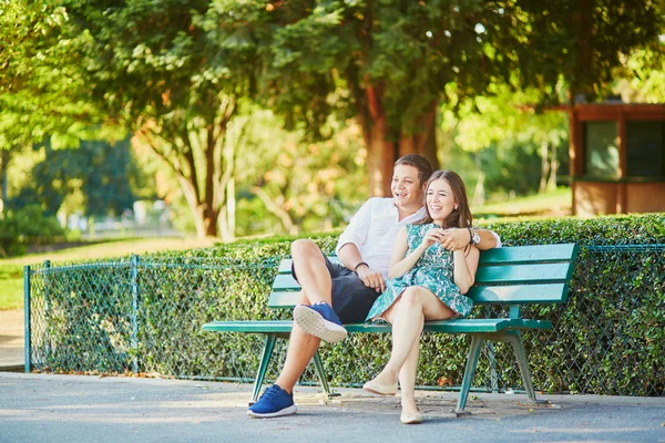Feliz pareja de citas en un banco en un parque parisino —  Fotos de Stock
