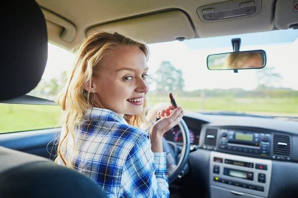 Красивая женщина наносит помаду в машине во время вождения — стоковое фото